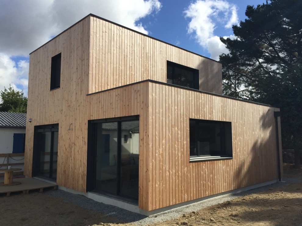 Small contemporary two-storey grey exterior in Nantes with wood siding and a flat roof.