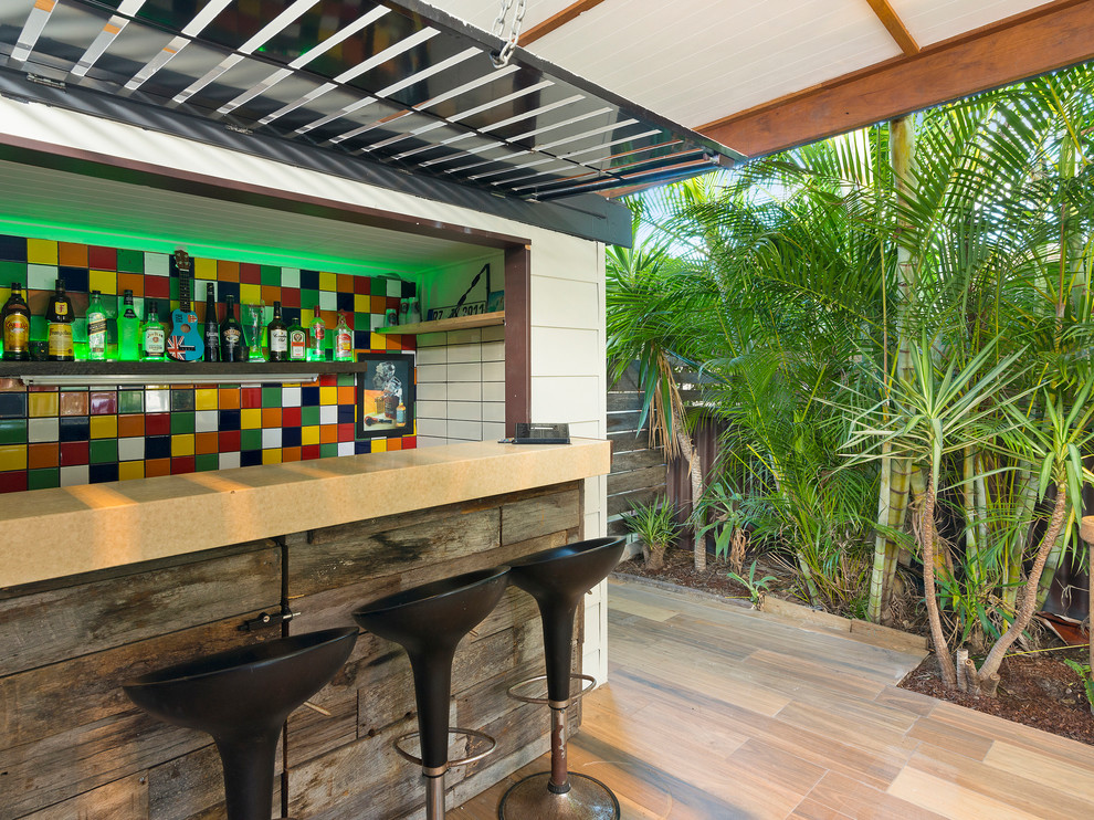 This is an example of a beach style seated home bar in Gold Coast - Tweed with multi-coloured splashback, beige floor, beige benchtop and mosaic tile splashback.