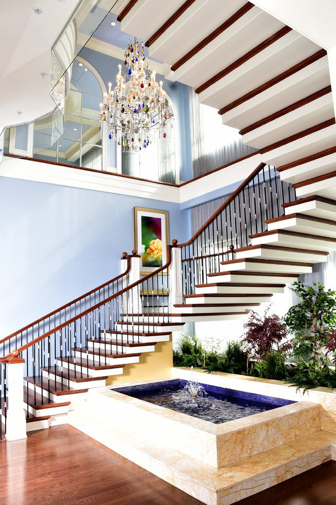 Photo of a large transitional wood curved staircase in Toronto with painted wood risers.