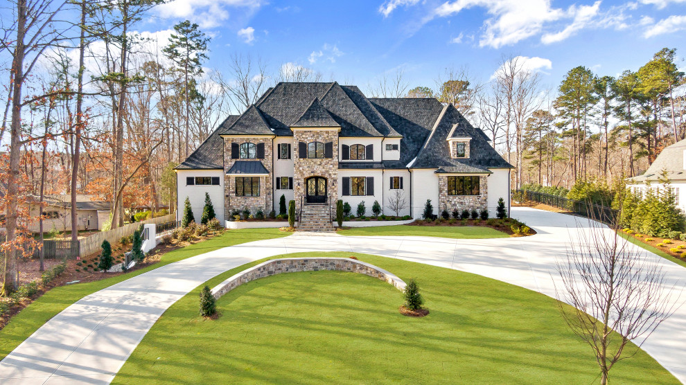 Photo of a large traditional three-storey white house exterior in Raleigh with stone veneer, a hip roof, a shingle roof and a black roof.