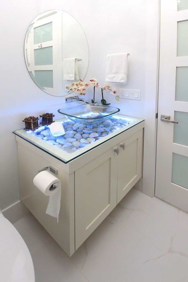 Photo of a mid-sized contemporary powder room in Vancouver with a one-piece toilet, grey walls, marble floors, a vessel sink, glass benchtops, grey floor and shaker cabinets.