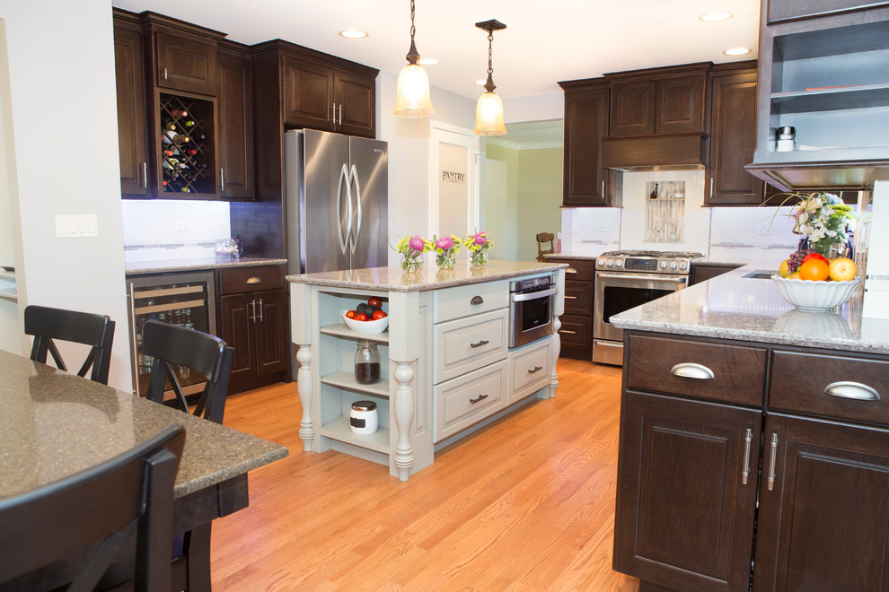 Example of a mid-sized transitional u-shaped light wood floor enclosed kitchen design in Chicago with an undermount sink, raised-panel cabinets, dark wood cabinets, quartz countertops, beige backsplash, ceramic backsplash, stainless steel appliances and an island