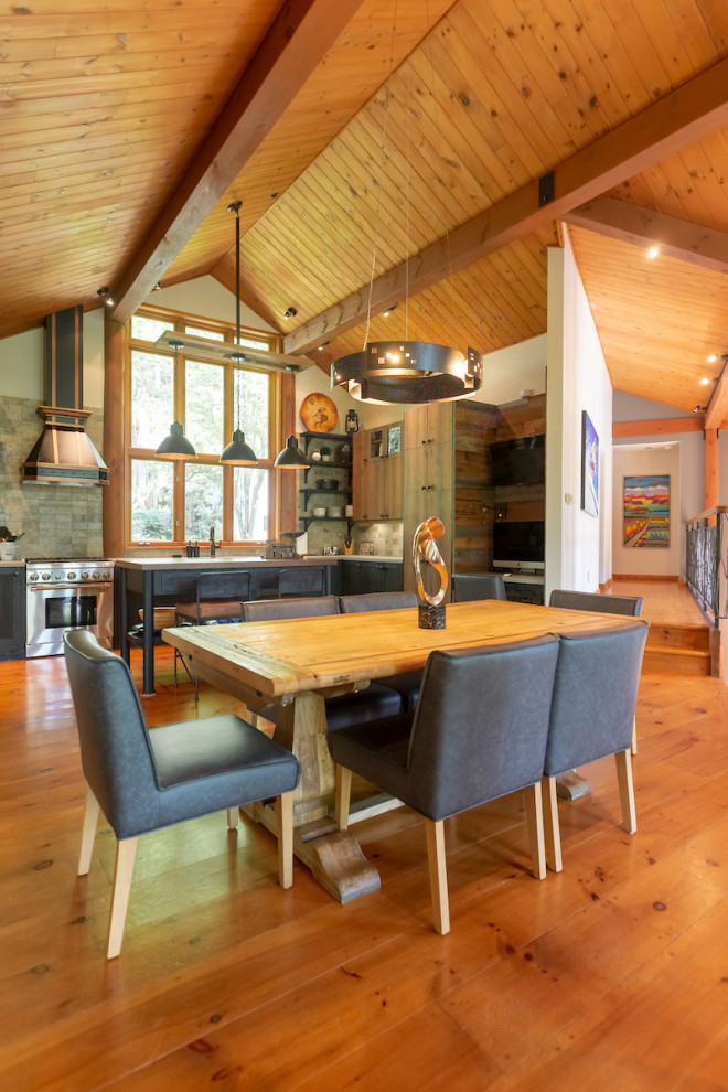 This is an example of a mid-sized country kitchen/dining combo in Montreal with white walls, medium hardwood floors, a stone fireplace surround and orange floor.