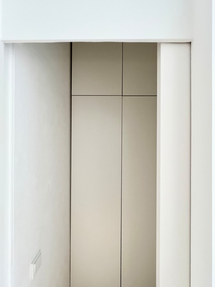 Kleiner Moderner Hauswirtschaftsraum in L-Form mit Waschmaschinenschrank, flächenbündigen Schrankfronten, weißen Schränken, weißer Wandfarbe, hellem Holzboden und braunem Boden in Berlin