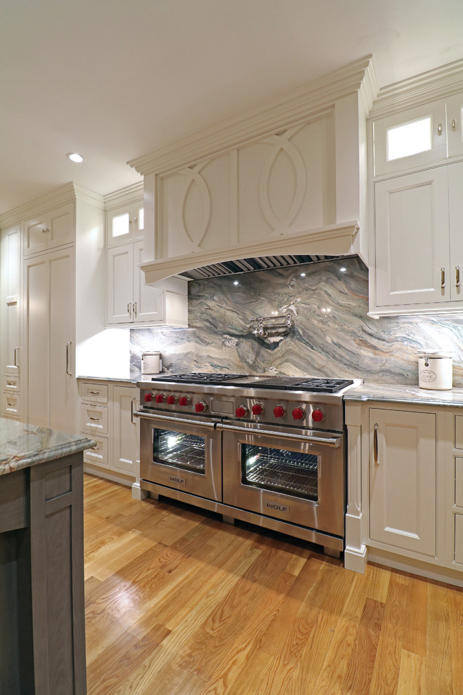 Photo of a large transitional single-wall eat-in kitchen in Boston with a farmhouse sink, beaded inset cabinets, white cabinets, granite benchtops, multi-coloured splashback, stone slab splashback, stainless steel appliances, light hardwood floors, multiple islands, yellow floor and multi-coloured benchtop.