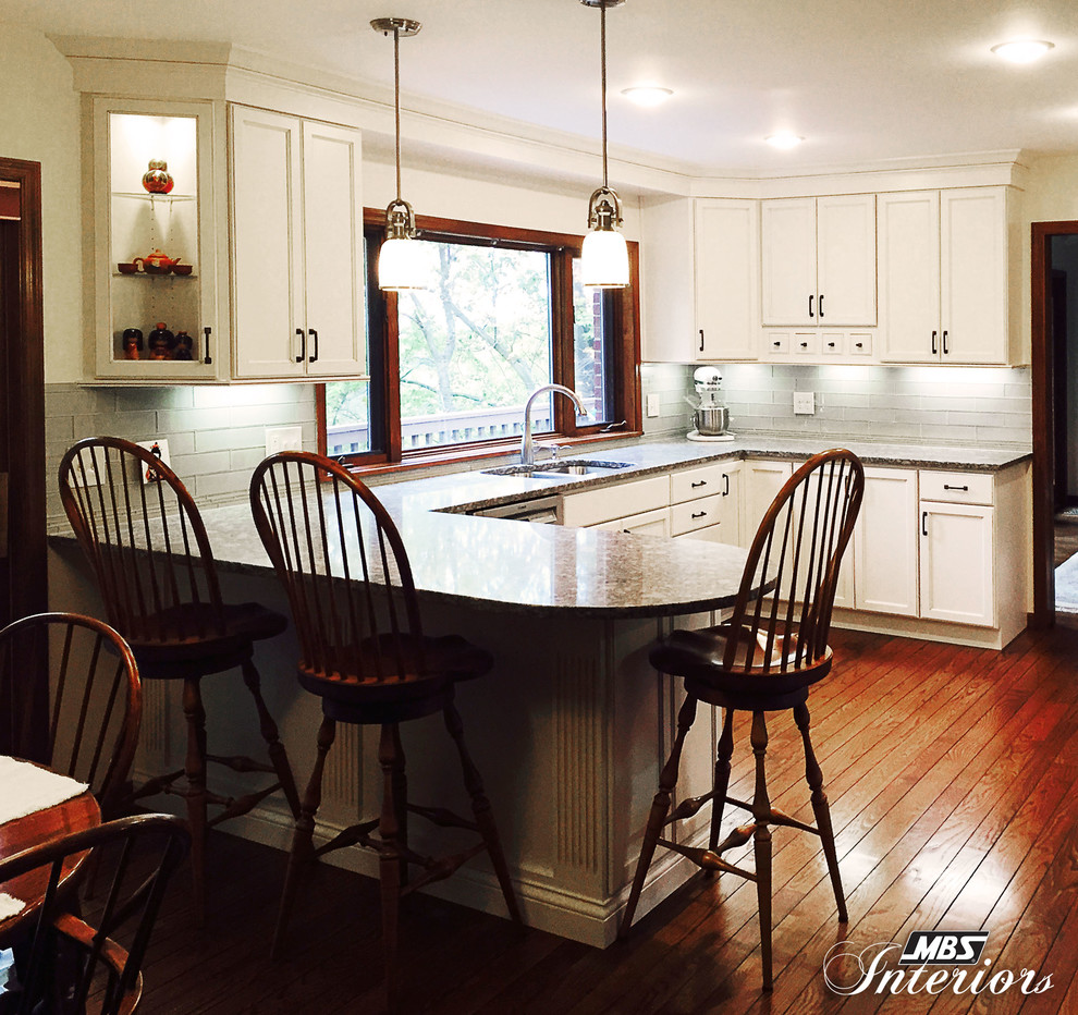 Transitional u-shaped enclosed kitchen photo with an undermount sink, flat-panel cabinets, white cabinets, quartz countertops, gray backsplash, subway tile backsplash, stainless steel appliances and a peninsula