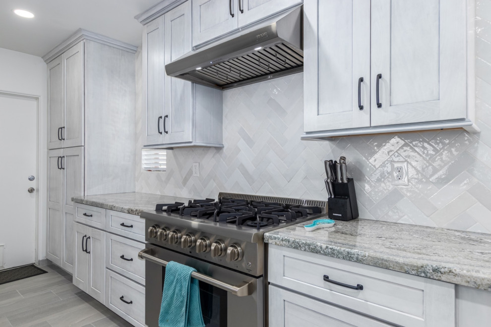 Transitional l-shaped kitchen photo in Phoenix with a single-bowl sink, shaker cabinets, white cabinets, granite countertops, white backsplash and stainless steel appliances