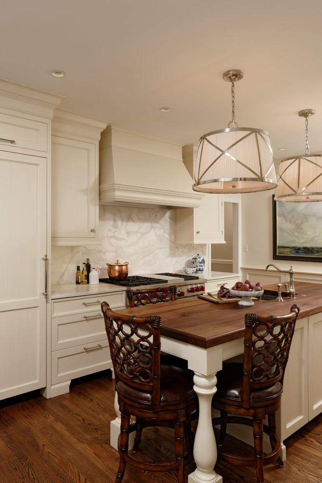 Mid-sized traditional u-shaped eat-in kitchen in DC Metro with marble benchtops, stone slab splashback, medium hardwood floors, with island, beaded inset cabinets, white cabinets, white splashback, stainless steel appliances and an undermount sink.