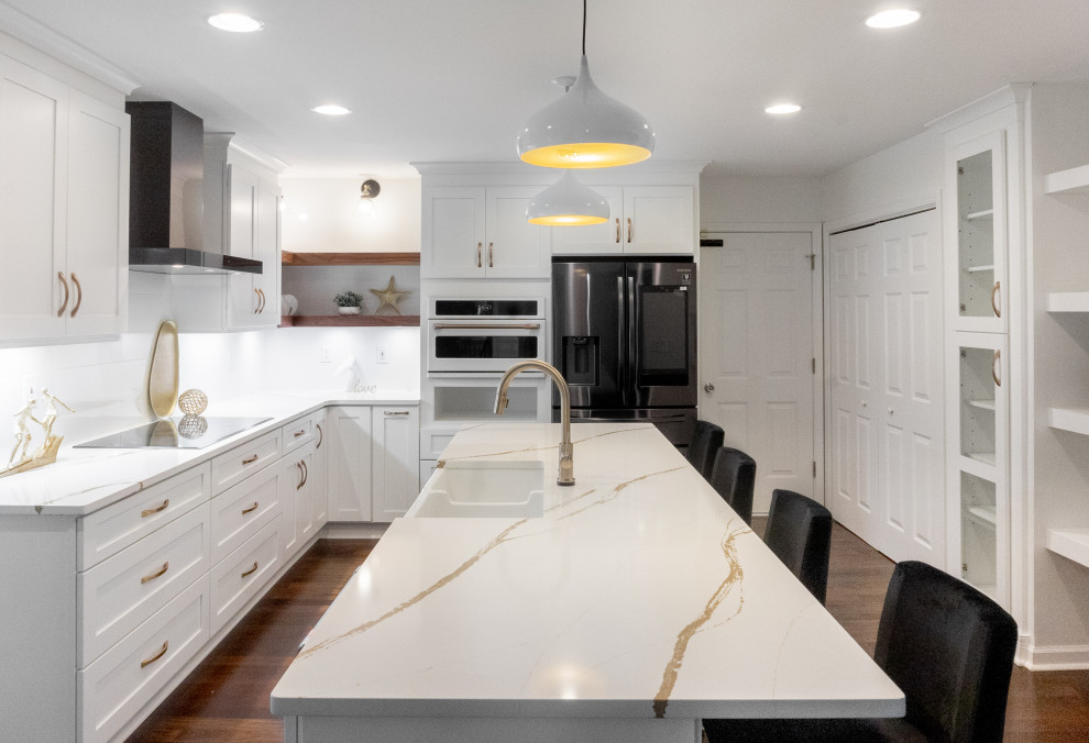 This is an example of a medium sized midcentury l-shaped open plan kitchen in Atlanta with a belfast sink, shaker cabinets, white cabinets, engineered stone countertops, white splashback, porcelain splashback, stainless steel appliances, dark hardwood flooring, an island, brown floors and white worktops.