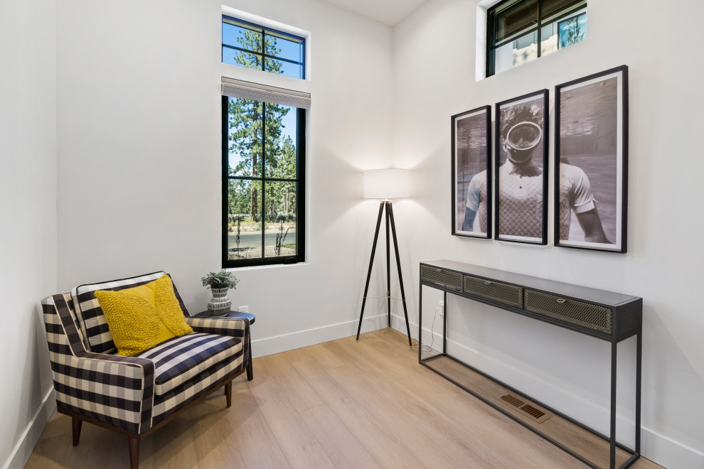 Mittelgroßes Modernes Arbeitszimmer mit Arbeitsplatz, weißer Wandfarbe, hellem Holzboden, freistehendem Schreibtisch und braunem Boden in Sonstige