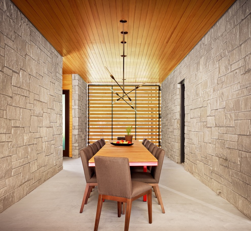 This is an example of a midcentury dining room in Austin with concrete floors.