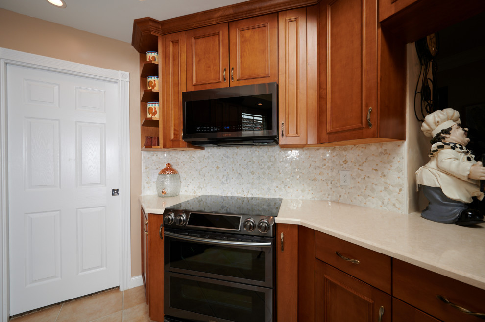 Example of a mid-sized transitional galley porcelain tile, beige floor and tray ceiling kitchen design with a farmhouse sink, recessed-panel cabinets, medium tone wood cabinets, quartz countertops, multicolored backsplash, marble backsplash, stainless steel appliances, a peninsula and beige countertops