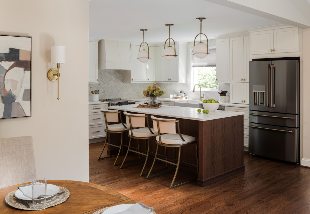 This is an example of a large transitional l-shaped eat-in kitchen in DC Metro with a farmhouse sink, shaker cabinets, white cabinets, marble benchtops, white splashback, marble splashback, stainless steel appliances, medium hardwood floors, with island, brown floor, white benchtop and vaulted.
