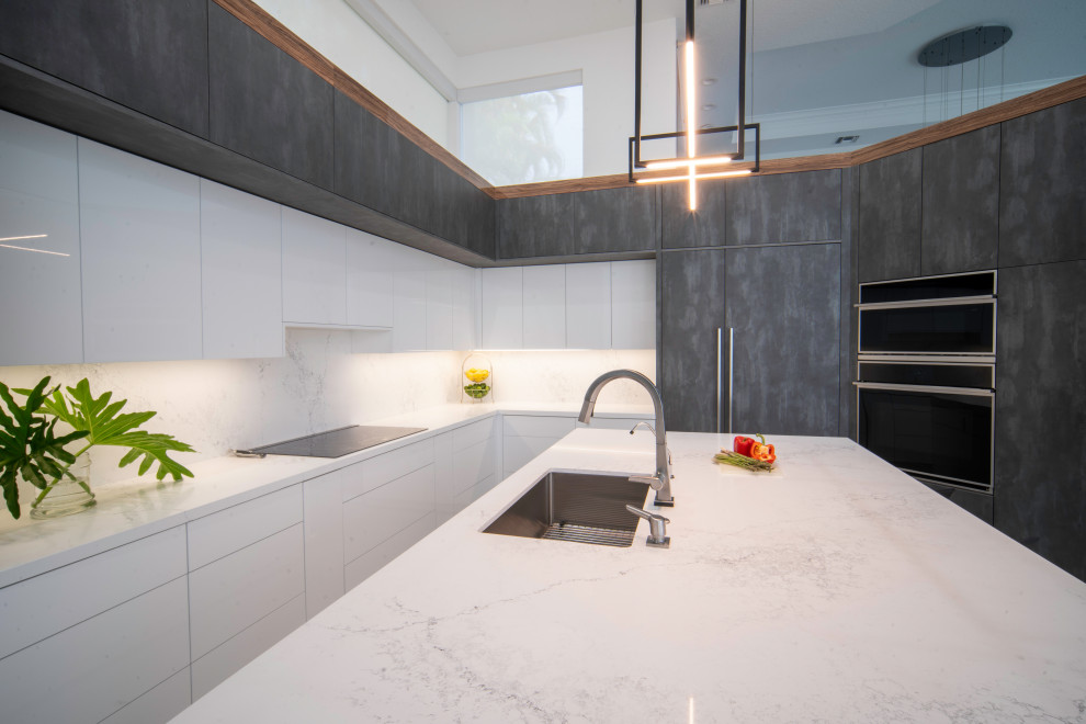 Modern inredning av ett stort vit vitt kök, med en undermonterad diskho, släta luckor, bänkskiva i kvartsit, vitt stänkskydd, stänkskydd i sten, integrerade vitvaror, klinkergolv i porslin, en köksö och grått golv