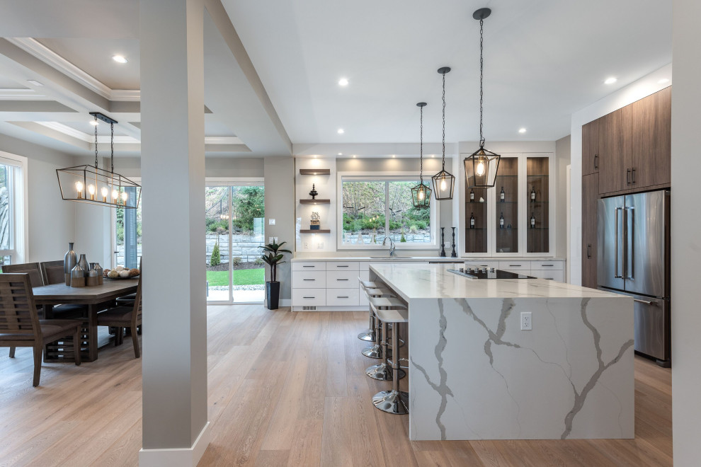 This is an example of a large contemporary l-shaped open plan kitchen in Vancouver with an undermount sink, marble benchtops, stainless steel appliances, light hardwood floors, with island, beige floor and white benchtop.