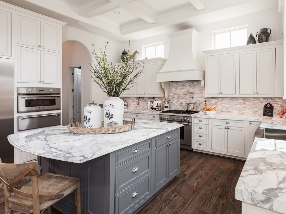 Design ideas for a mid-sized traditional u-shaped kitchen in Houston with a farmhouse sink, white cabinets, marble benchtops, multi-coloured splashback, glass tile splashback, stainless steel appliances, dark hardwood floors, with island and beaded inset cabinets.