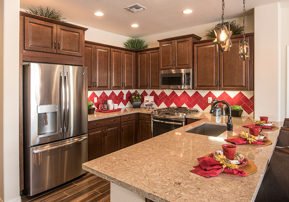 Mid-sized transitional u-shaped ceramic tile and brown floor eat-in kitchen photo in Phoenix with an undermount sink, raised-panel cabinets, dark wood cabinets, solid surface countertops, red backsplash, ceramic backsplash, stainless steel appliances and no island