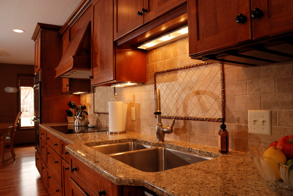Design ideas for a mid-sized traditional galley eat-in kitchen in Minneapolis with an undermount sink, shaker cabinets, medium wood cabinets, granite benchtops, beige splashback, stone tile splashback, stainless steel appliances and medium hardwood floors.