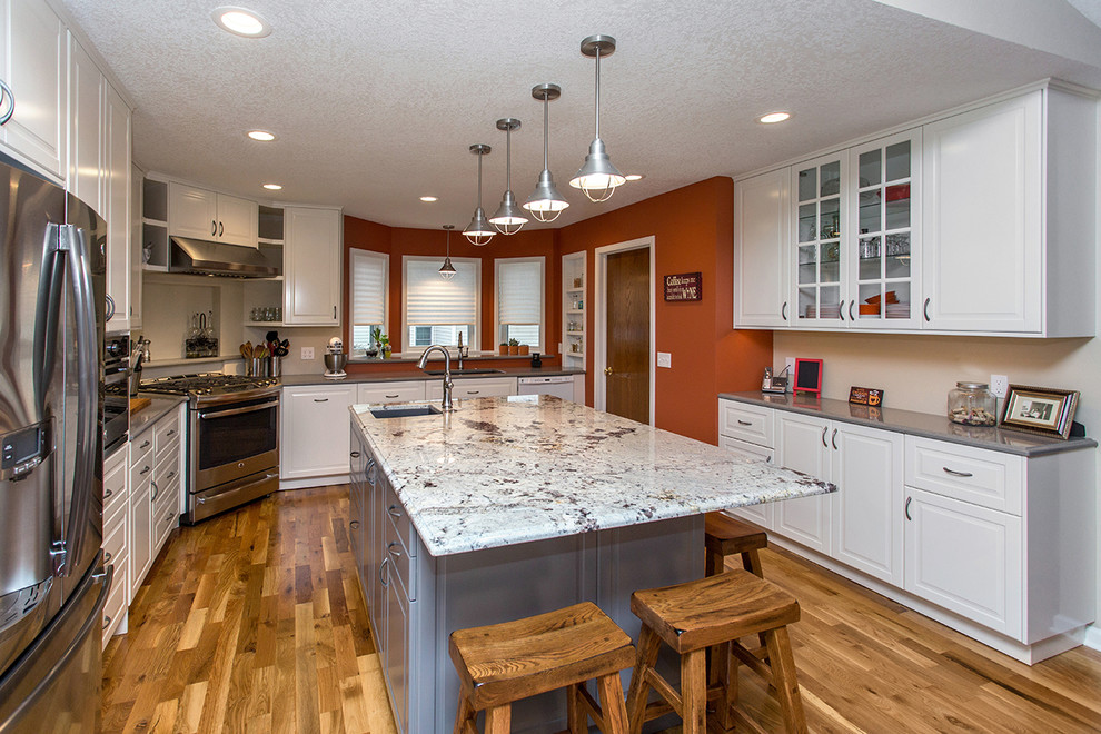 Inspiration for a mid-sized transitional u-shaped medium tone wood floor open concept kitchen remodel with an undermount sink, raised-panel cabinets, white cabinets, quartz countertops, gray backsplash, porcelain backsplash, stainless steel appliances and an island