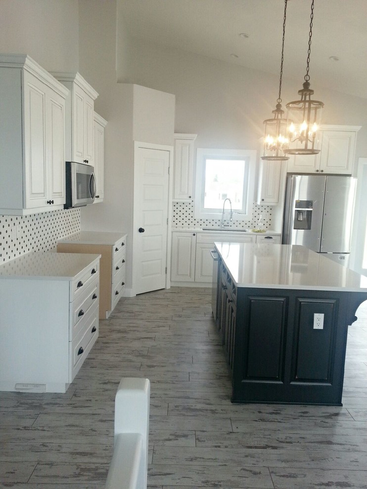 Photo of a mid-sized transitional l-shaped open plan kitchen in Calgary with an undermount sink, raised-panel cabinets, white cabinets, quartz benchtops, white splashback, ceramic splashback, stainless steel appliances, porcelain floors, with island and grey floor.