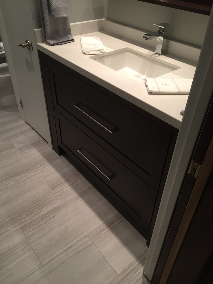 This is an example of a mid-sized transitional 3/4 bathroom in Toronto with shaker cabinets, black cabinets, an alcove shower, a bidet, gray tile, ceramic tile, grey walls, ceramic floors, an undermount sink, engineered quartz benchtops, grey floor and a hinged shower door.