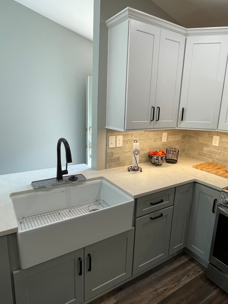 Eat-in kitchen - mid-sized transitional u-shaped vinyl floor and brown floor eat-in kitchen idea with a farmhouse sink, shaker cabinets, white cabinets, quartz countertops, gray backsplash, subway tile backsplash, stainless steel appliances, no island and white countertops