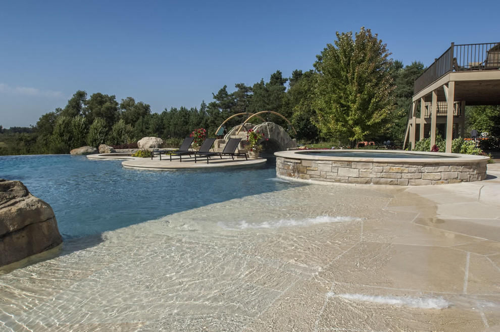 Example of a huge backyard stone and custom-shaped infinity hot tub design in Chicago
