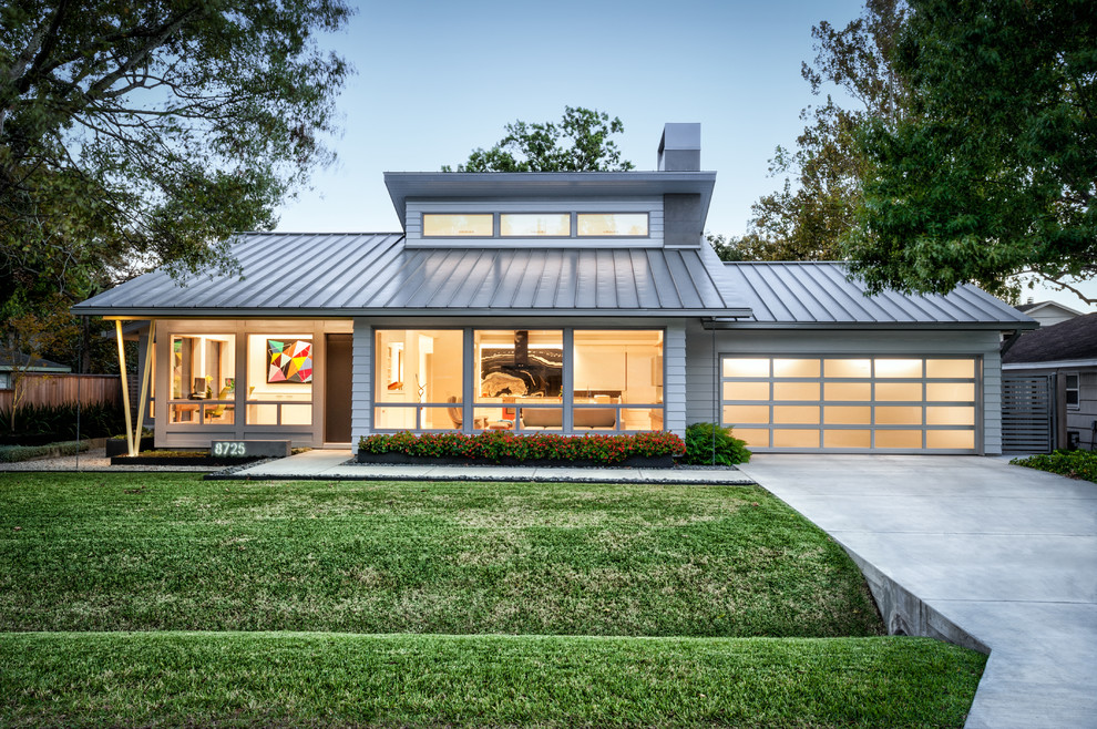 Photo of a midcentury one-storey grey house exterior in Houston with concrete fiberboard siding, a hip roof and a metal roof.