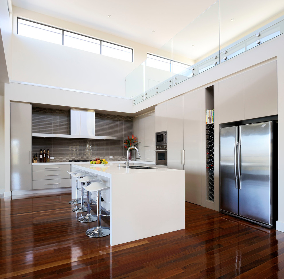Large contemporary l-shaped kitchen in Melbourne with an undermount sink, flat-panel cabinets, grey cabinets, grey splashback, ceramic splashback, stainless steel appliances, dark hardwood floors and with island.