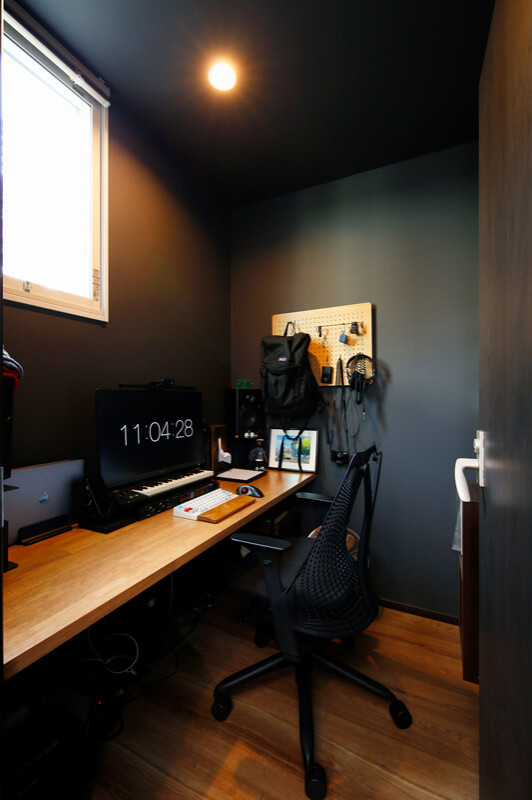 This is an example of a small modern study room in Other with black walls, dark hardwood floors, brown floor, wallpaper and wallpaper.