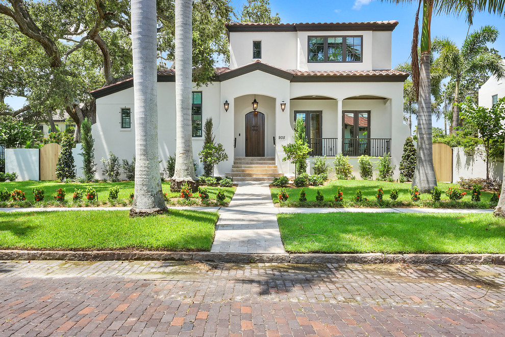 Mediterranean two-storey white house exterior in Tampa with a gable roof and a tile roof.