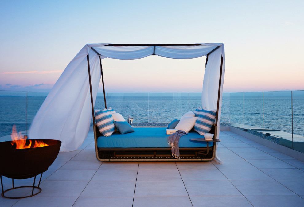 Immagine di una terrazza minimal di medie dimensioni con un focolare, nessuna copertura e parapetto in vetro