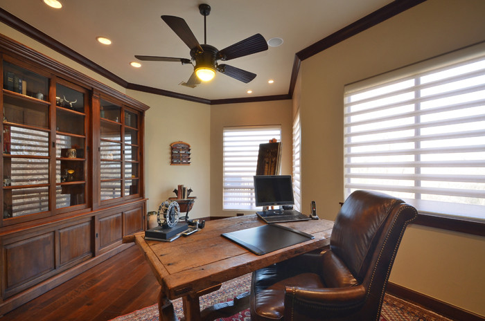 Inspiration for a mid-sized mediterranean home office in Austin with medium hardwood floors, no fireplace, a freestanding desk, brown floor and beige walls.