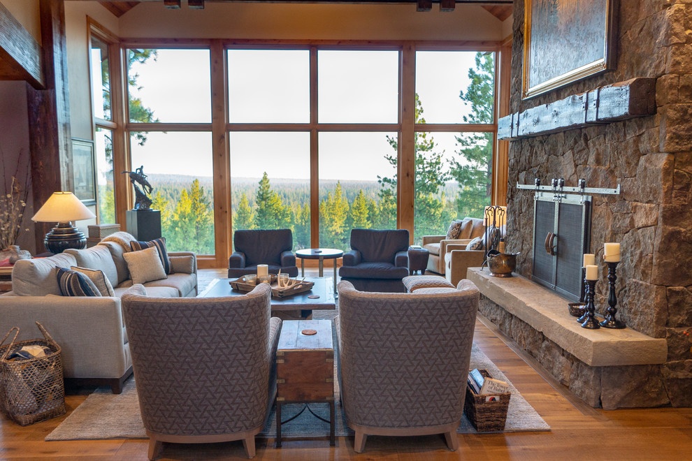 This is an example of a large country open concept living room in Other with brown walls, medium hardwood floors, a standard fireplace, a stone fireplace surround and brown floor.