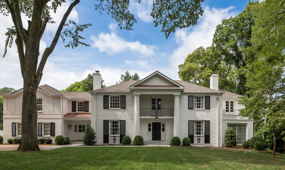 Large traditional two-storey white house exterior in Nashville with stone veneer, a hip roof and a shingle roof.