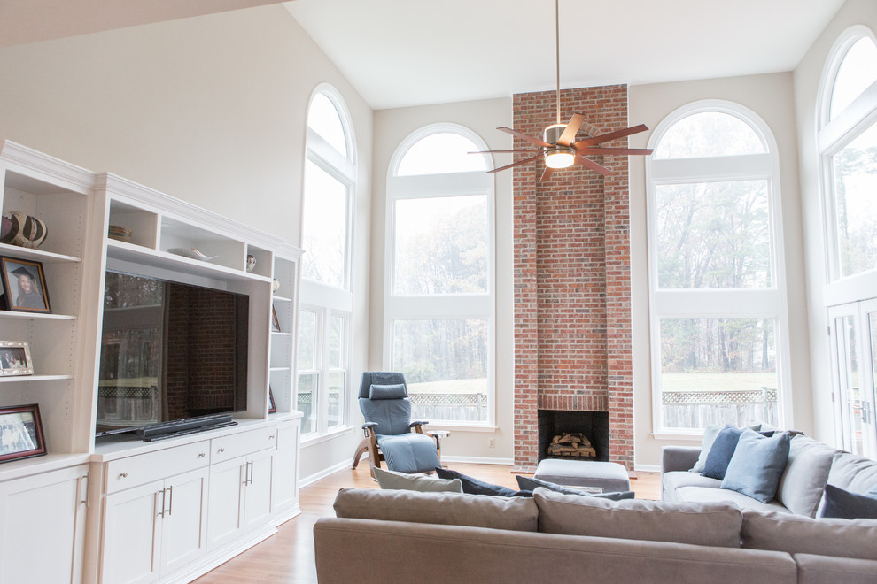 This is an example of a large transitional open concept living room in DC Metro with beige walls, medium hardwood floors, a standard fireplace, a brick fireplace surround and a built-in media wall.
