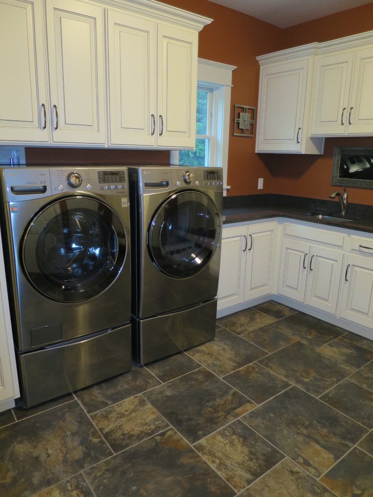 This is an example of a large transitional l-shaped utility room in Other with an undermount sink, raised-panel cabinets, white cabinets, granite benchtops, orange walls, porcelain floors and a side-by-side washer and dryer.