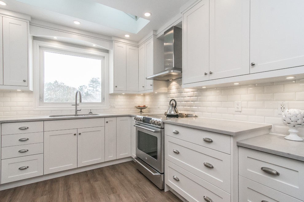 Small transitional u-shaped eat-in kitchen in Toronto with an undermount sink, shaker cabinets, white cabinets, quartz benchtops, white splashback, ceramic splashback, stainless steel appliances, cork floors and no island.