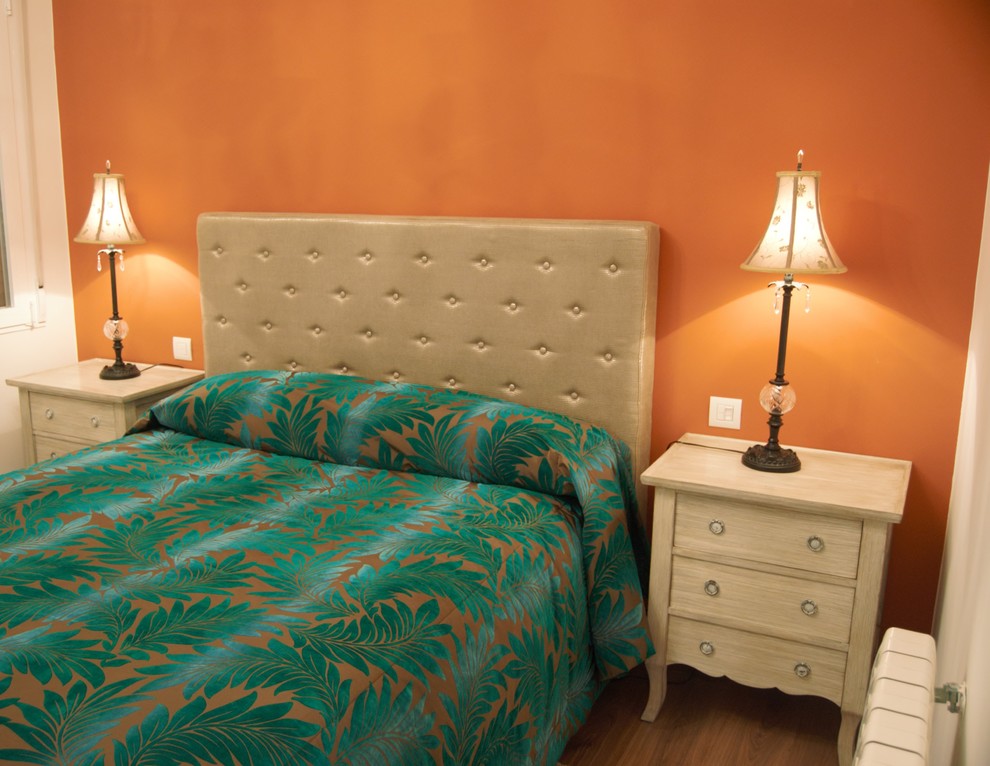 Modelo de habitación de invitados clásica renovada de tamaño medio con parades naranjas, suelo laminado y suelo marrón