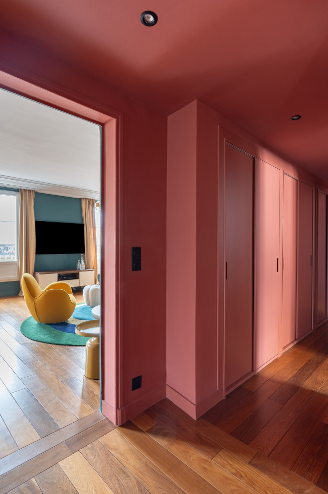 Стильный дизайн: большой коридор в современном стиле с красными стенами, темным паркетным полом и коричневым полом - последний тренд