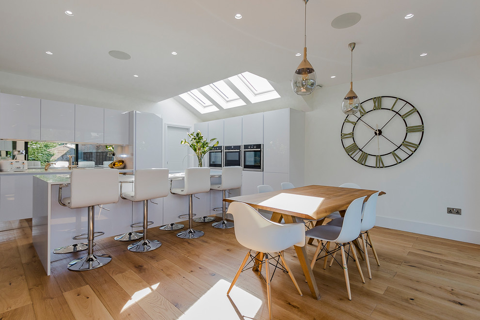 Inspiration for a large contemporary eat-in kitchen in London with an undermount sink, white cabinets, quartz benchtops, panelled appliances, light hardwood floors and with island.