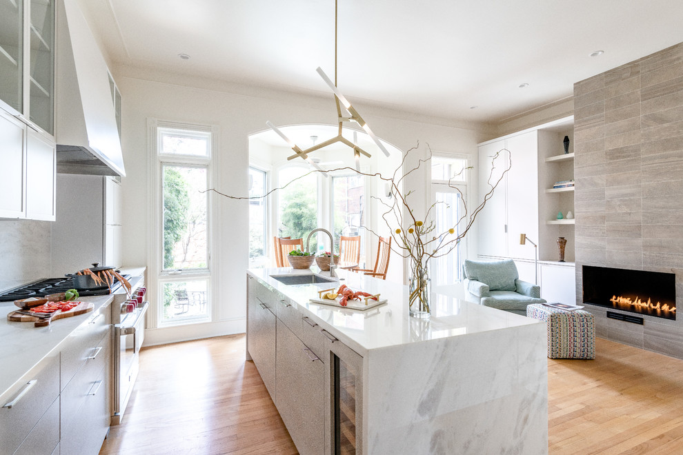 Photo of a mid-sized modern galley eat-in kitchen in DC Metro with a single-bowl sink, flat-panel cabinets, light wood cabinets, marble benchtops, grey splashback, marble splashback, stainless steel appliances, dark hardwood floors, with island, brown floor and white benchtop.