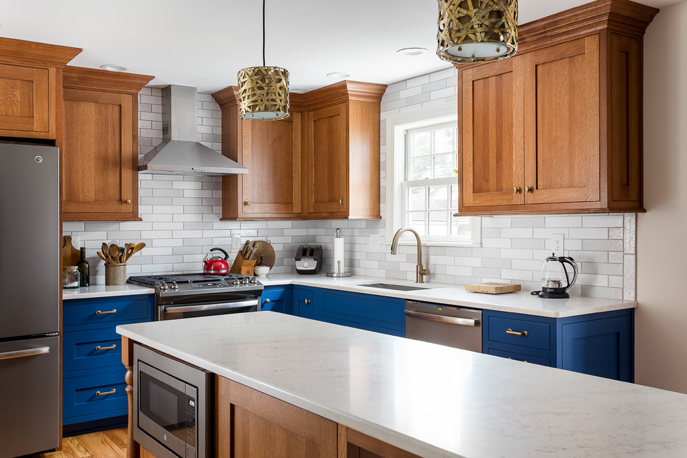 Photo of a small traditional l-shaped kitchen in Louisville with an undermount sink, shaker cabinets, blue cabinets, quartz benchtops, grey splashback, subway tile splashback, stainless steel appliances, brown floor, white benchtop, medium hardwood floors and with island.