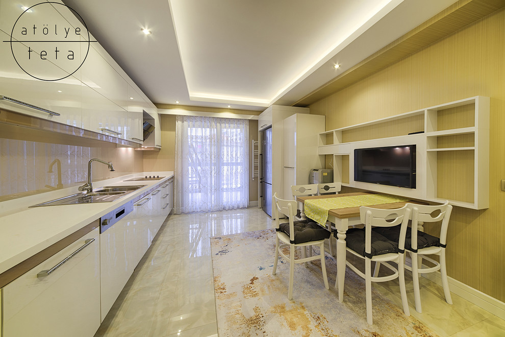 Photo of a mid-sized modern l-shaped separate kitchen in Other with a double-bowl sink, flat-panel cabinets, white cabinets, solid surface benchtops, slate splashback, stainless steel appliances, ceramic floors, no island, beige floor and white benchtop.