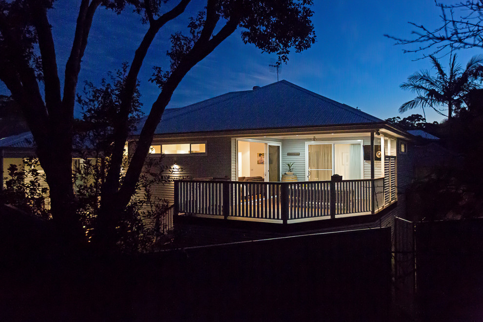 This is an example of a mid-sized contemporary one-storey blue house exterior in Sydney with wood siding, a hip roof and a metal roof.