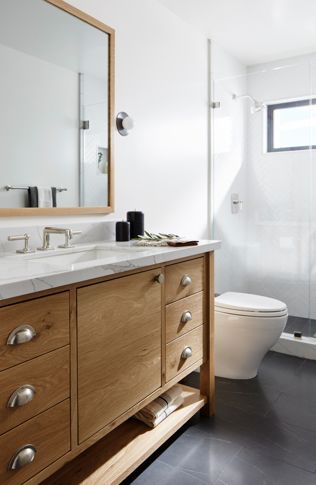 Inspiration for a mid-sized contemporary 3/4 bathroom in San Francisco with furniture-like cabinets, medium wood cabinets, an alcove shower, a one-piece toilet, white walls, slate floors, an undermount sink, marble benchtops, black floor and white benchtops.
