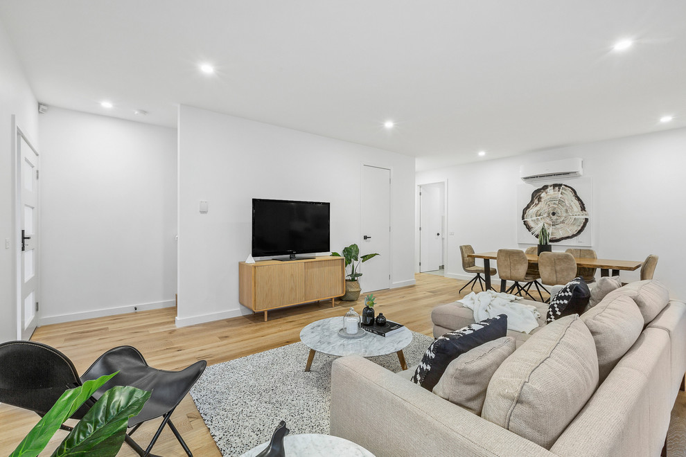 Small contemporary open concept living room in Melbourne with white walls and light hardwood floors.