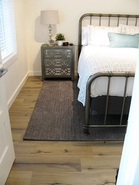 Photo of a mid-sized traditional guest bedroom in Portland with white walls, laminate floors, no fireplace and brown floor.