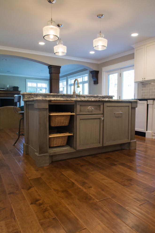 Inspiration for a mid-sized transitional l-shaped eat-in kitchen in Minneapolis with an undermount sink, shaker cabinets, white cabinets, granite benchtops, grey splashback, subway tile splashback, panelled appliances, with island, brown floor and dark hardwood floors.