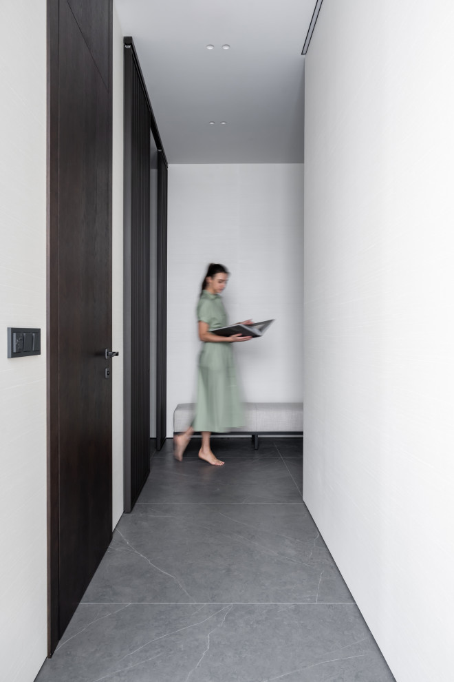 Cette photo montre une entrée tendance de taille moyenne avec un couloir, un mur beige, un sol en carrelage de porcelaine, une porte simple, une porte en bois brun, un sol gris et du papier peint.